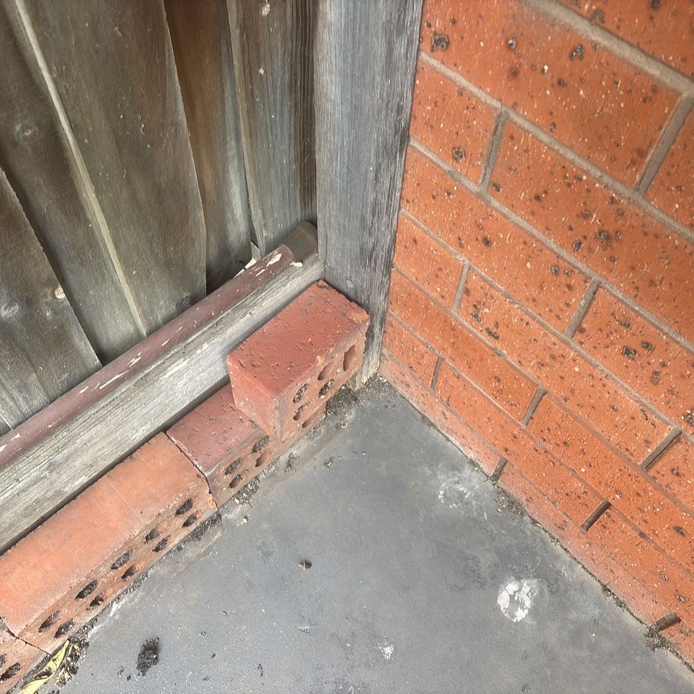 Downpipe discharging at the wall base, a condition termites like, found during a building and pest inspection in Braybrook